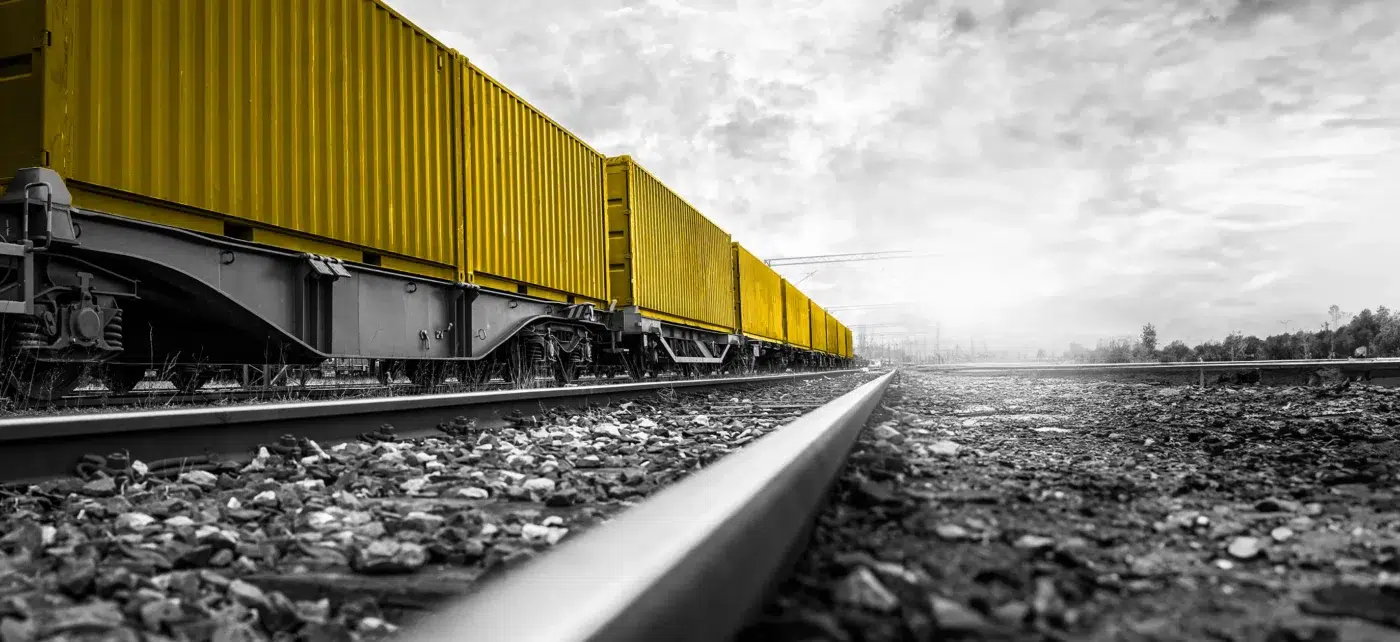 Black and white photo of a train moving shipping containers. Shipping containers colored yellow.